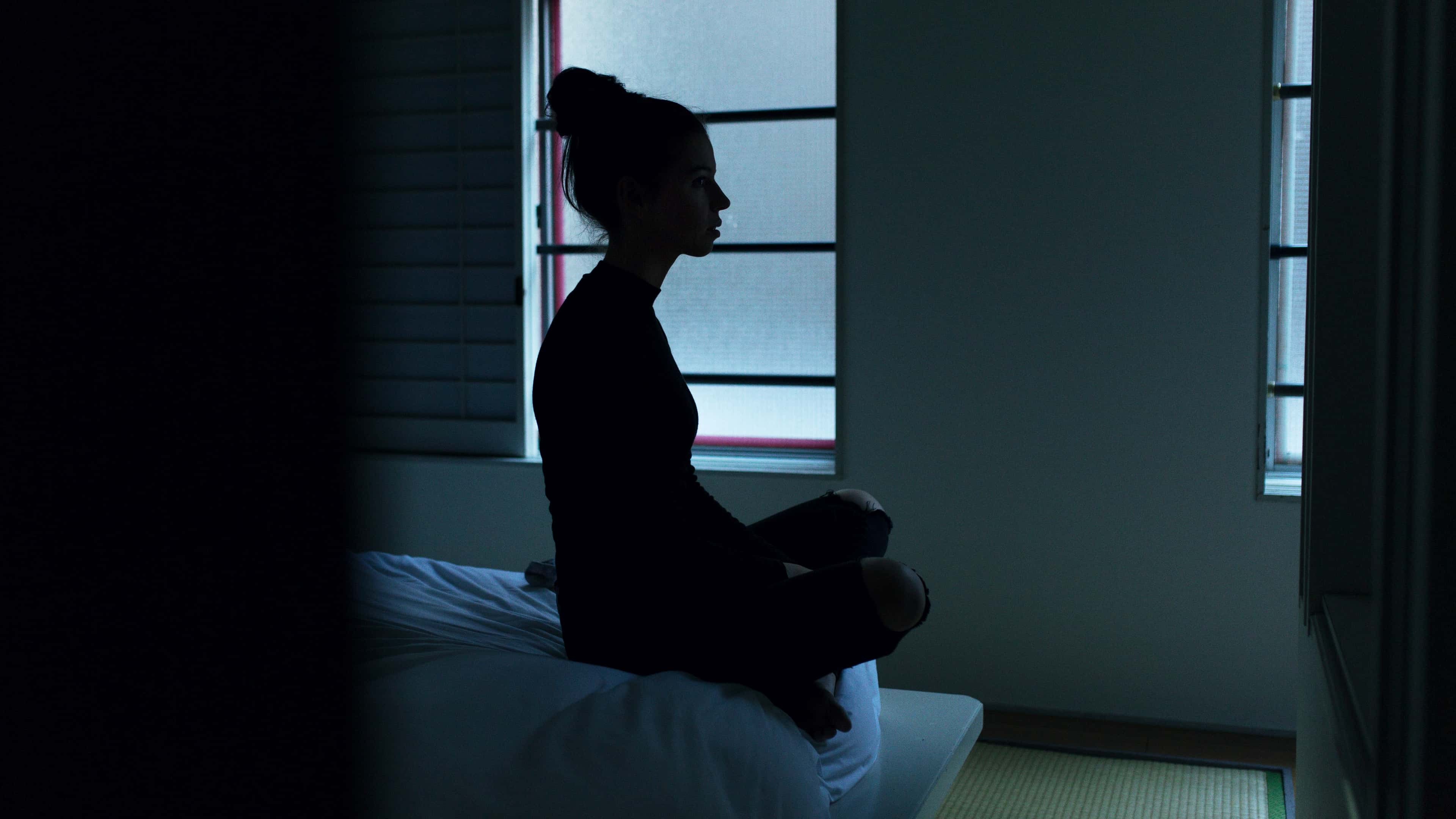 A woman sitting quietly by a window in the early morning