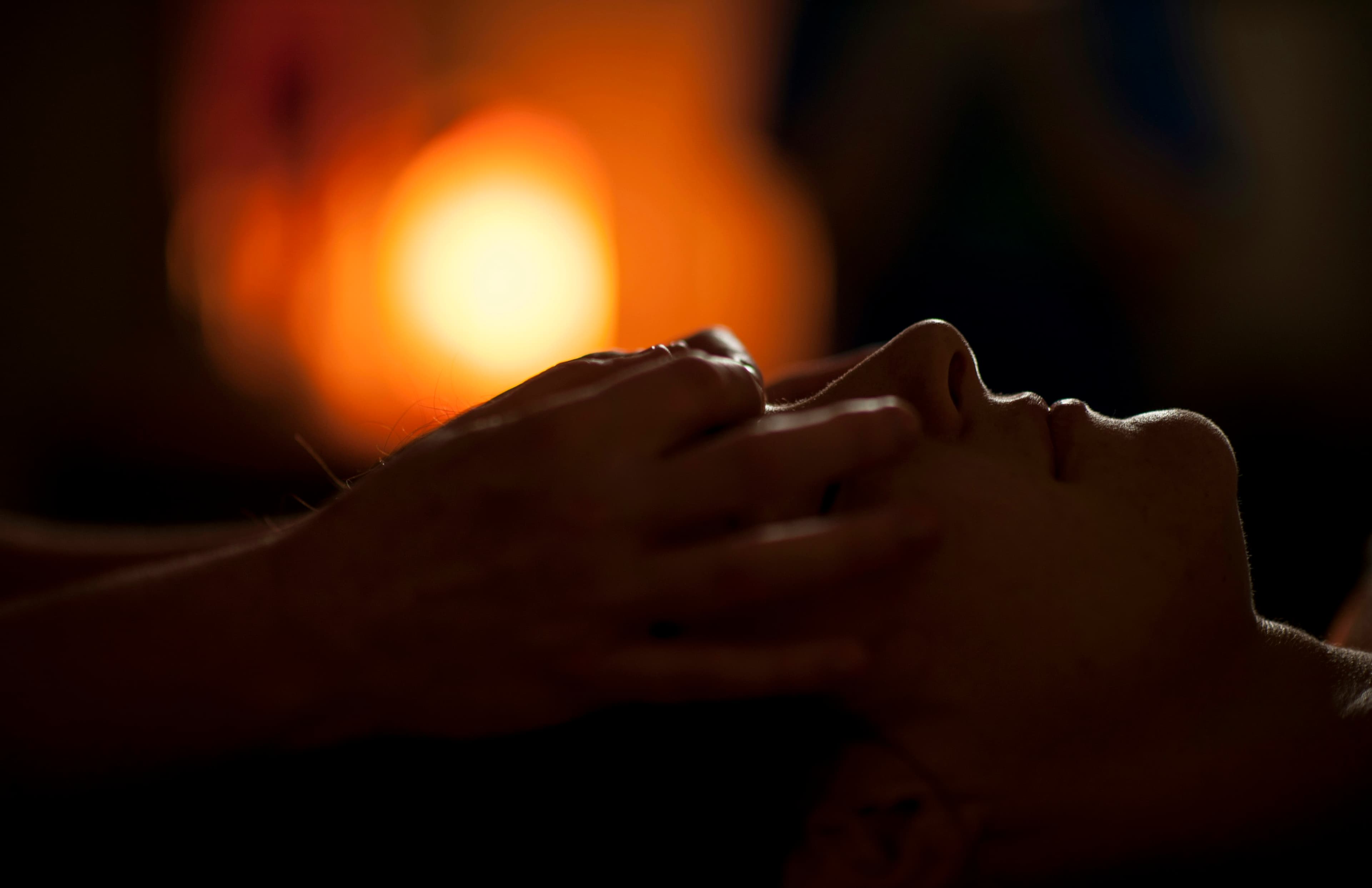 Hands resting gently on a client's face in warm, low light